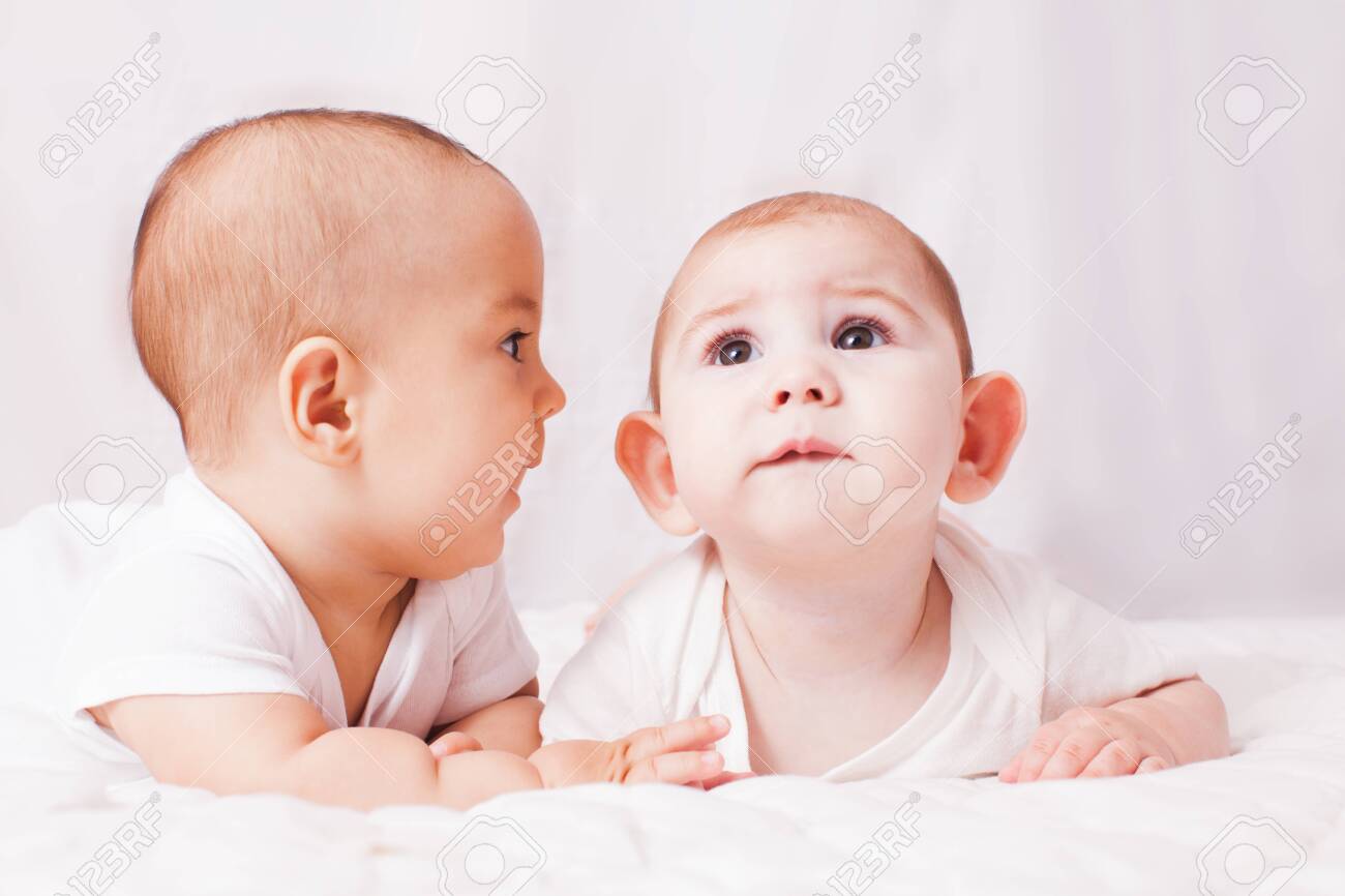 Babies talking, two babies lying on the bed - 140135209 Babies talking, two babies lying on the bed - 140135209