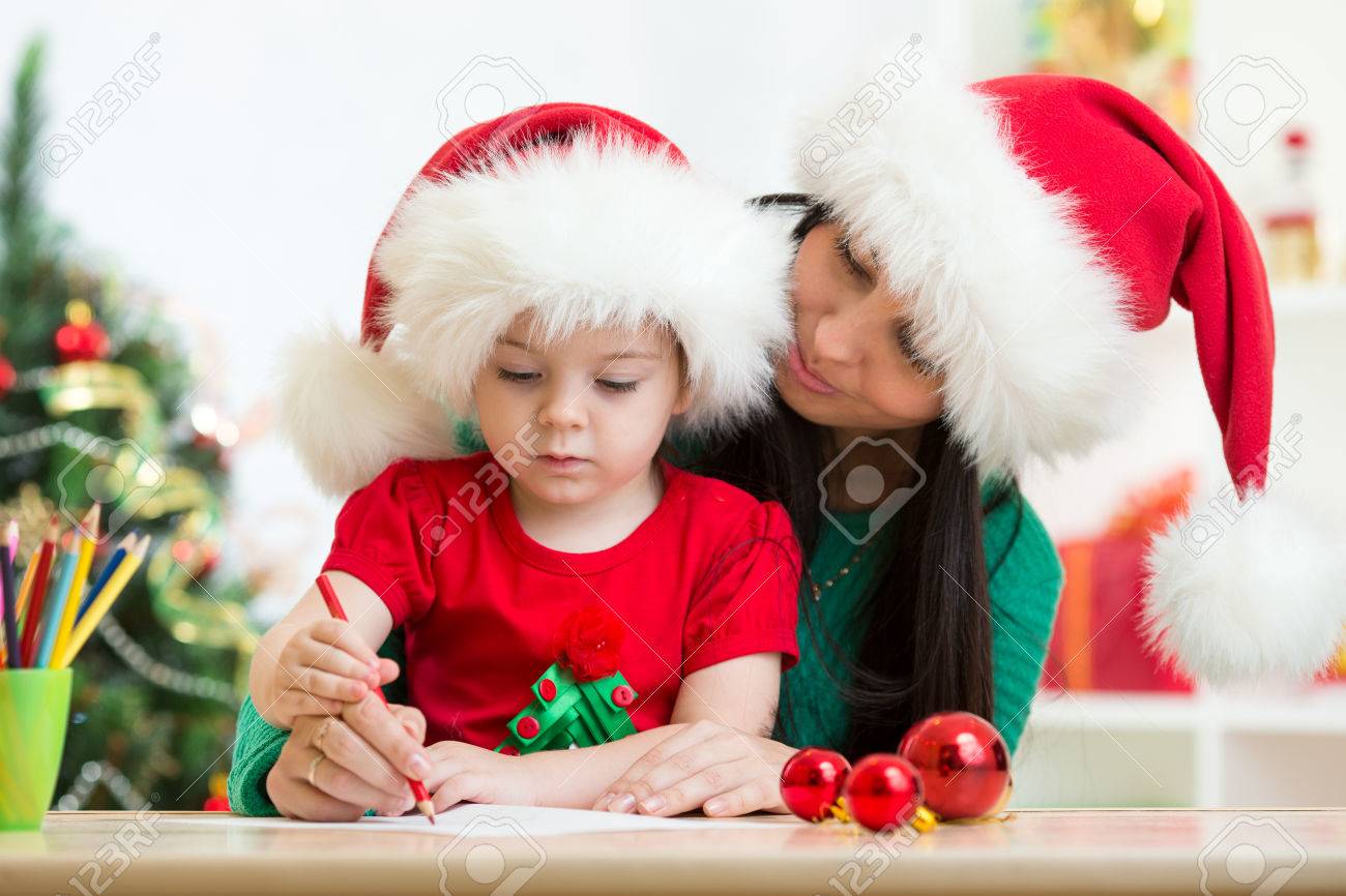 child girl and mom writing christmas letter to santa claus stock