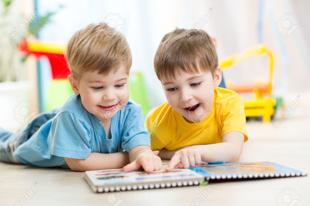 happy kids boys brothers reading together at home stock photo