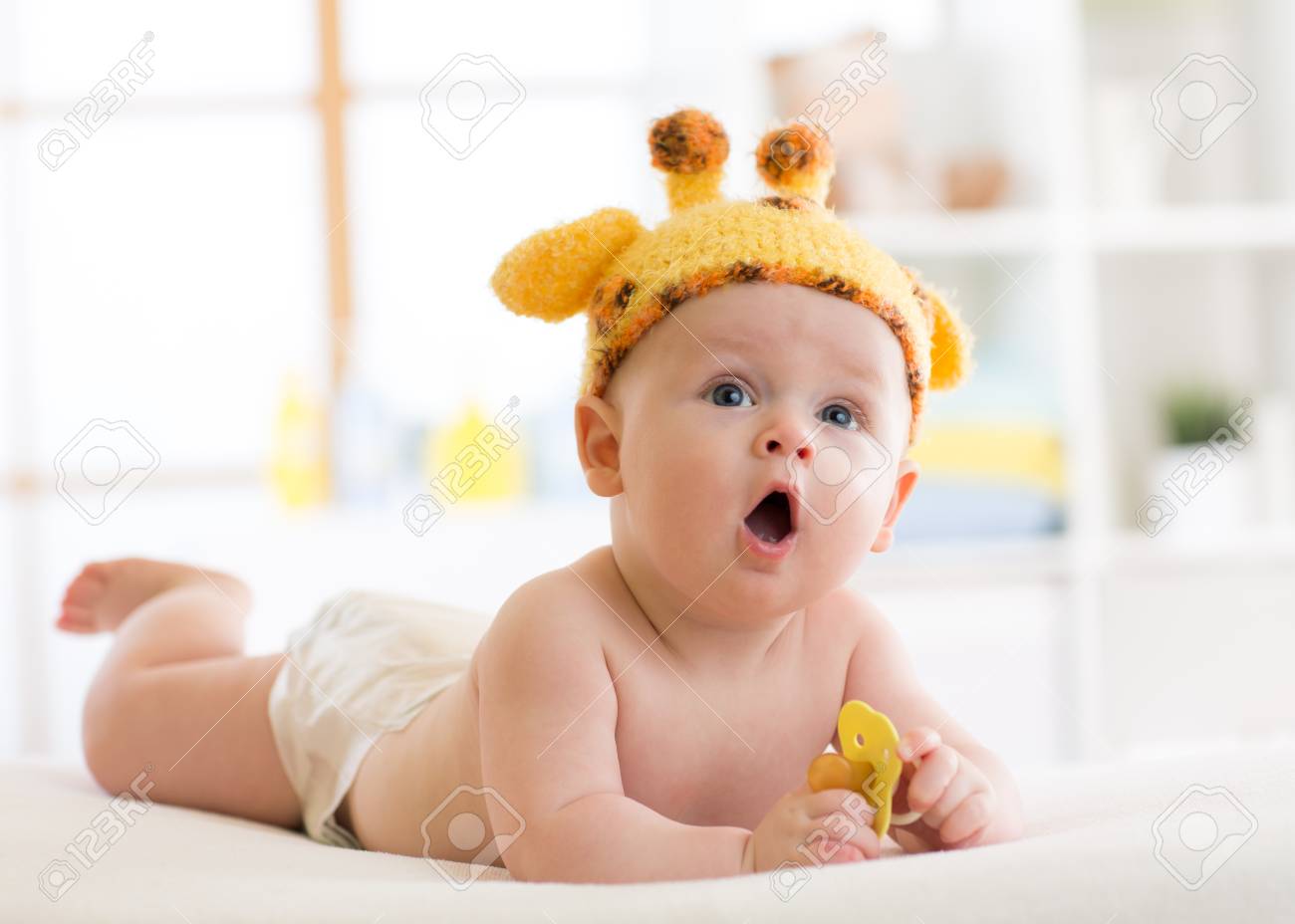 Funny Baby Boy In Giraffe Hat Lying On His Belly In Nursery Little Kid Lies Funny Baby Boy In Giraffe Hat Lying On His Belly In Nursery Little Kid Lies