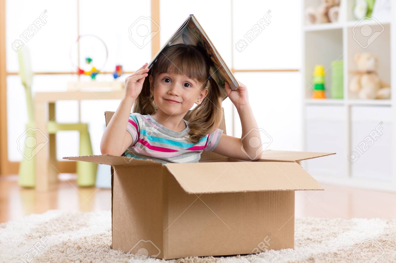 Niña niño jugando en una casa de juguete en la habitación de los niños Niña niño jugando en una casa de juguete en la habitación de los niños