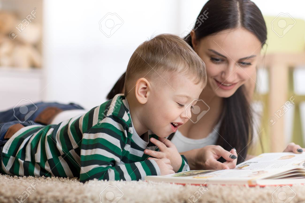 若いお母さんと彼女の子供の息子は床に横たわって本を読んでいます の写真素材 画像素材 Image