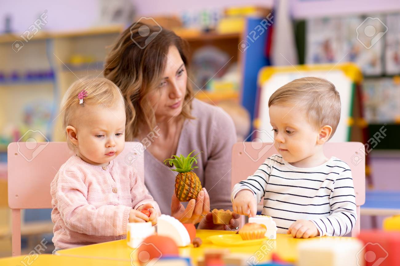 preschool teacher with babies toddlers playing with colorful teacher toddler