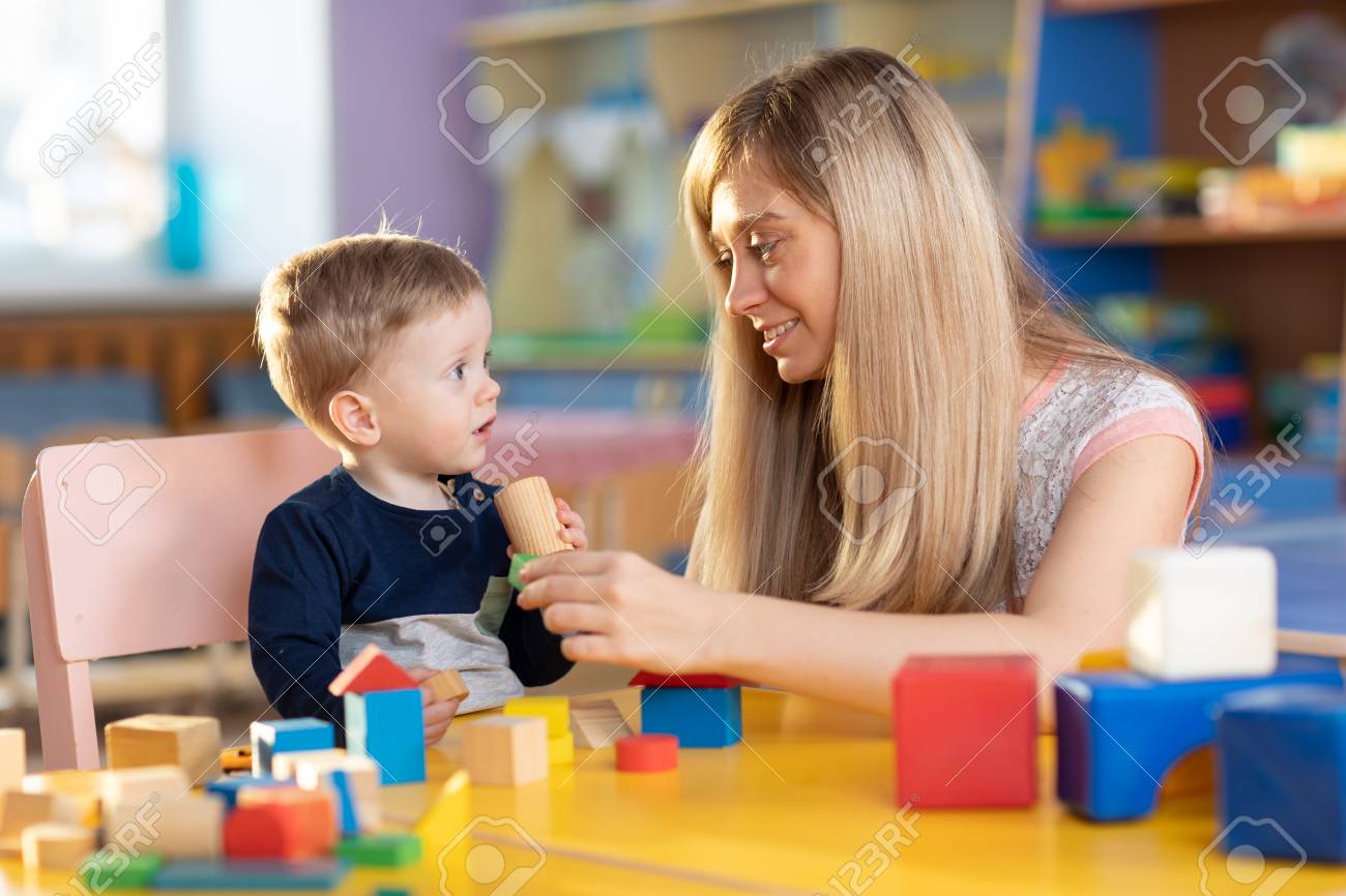 cute kindergarten teacher and baby toddler playing educational teacher toddler