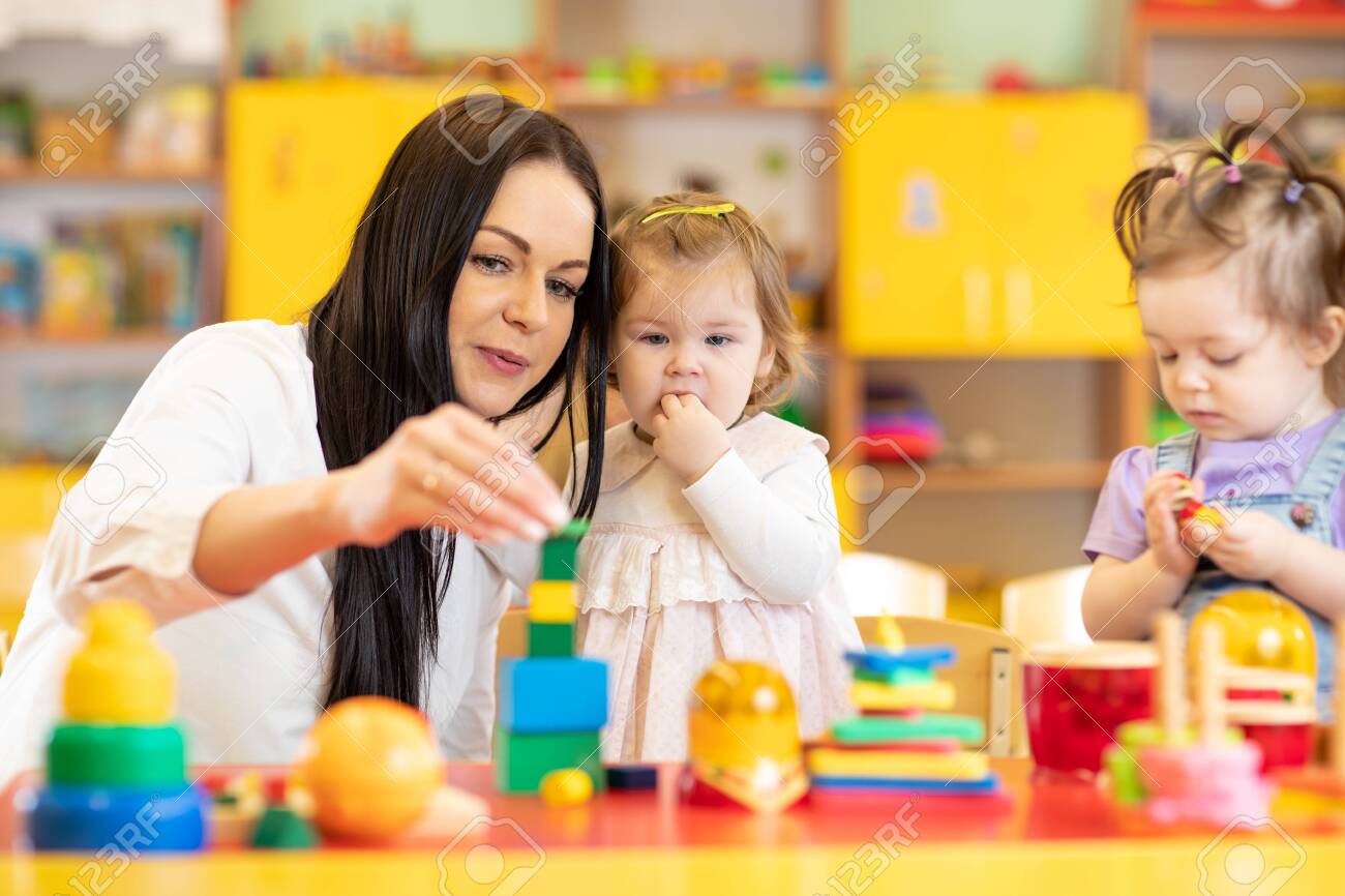 nursery teacher looking after children in daycare little kids teacher toddler