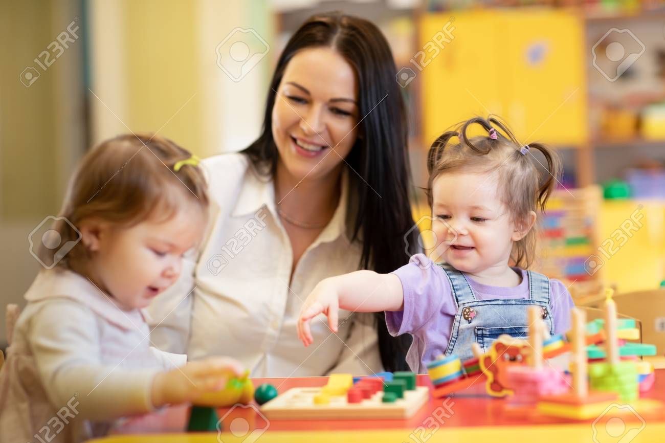 nursery teacher looking after children in daycare little kids teacher toddler