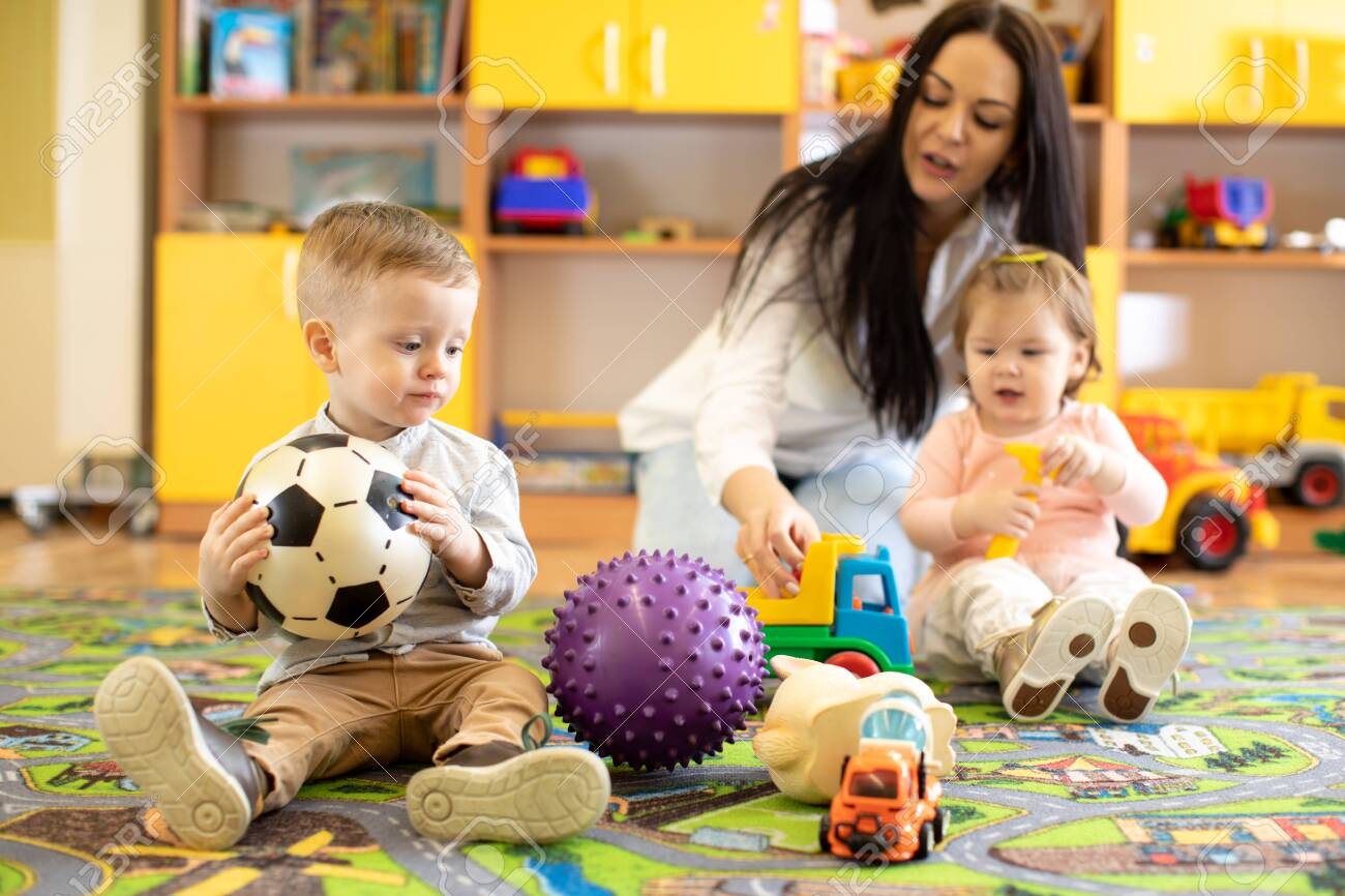 nursery teacher looking after children in kindergarten little teacher toddler