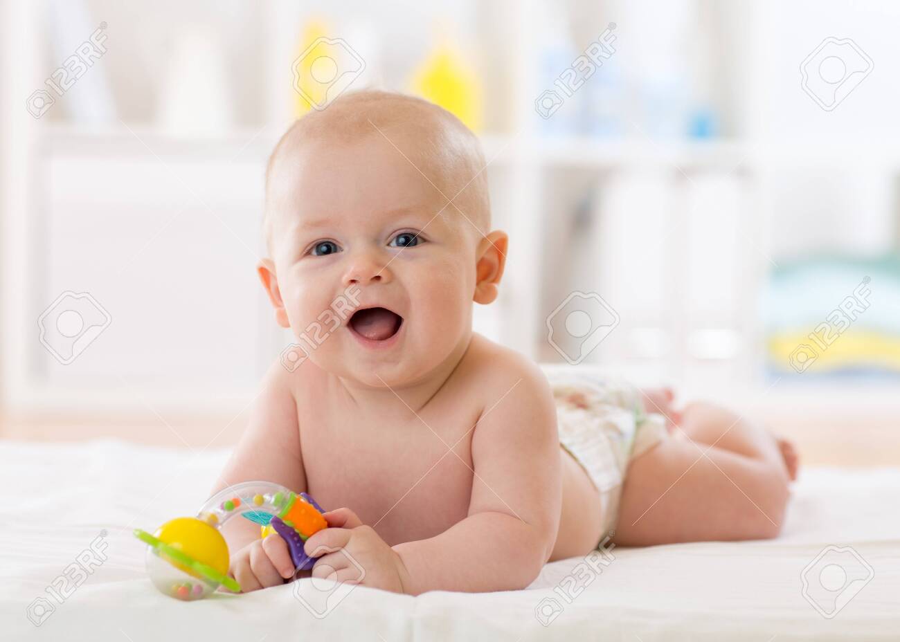 baby infant lying on belly weared diaper with teether - 131206474 baby infant lying on belly weared diaper with teether - 131206474