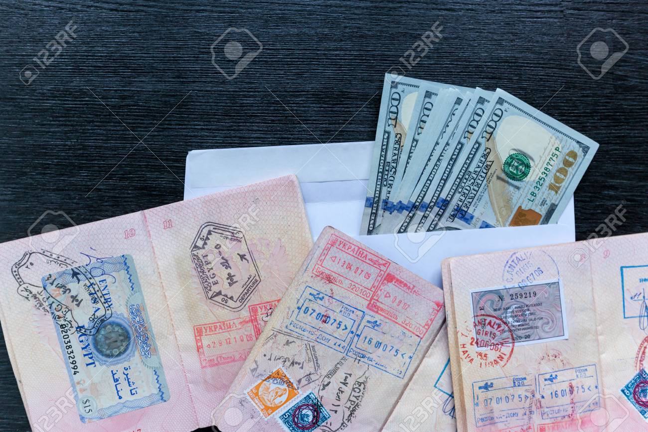 visas in foreign passports and an envelope with money are on envelope with money