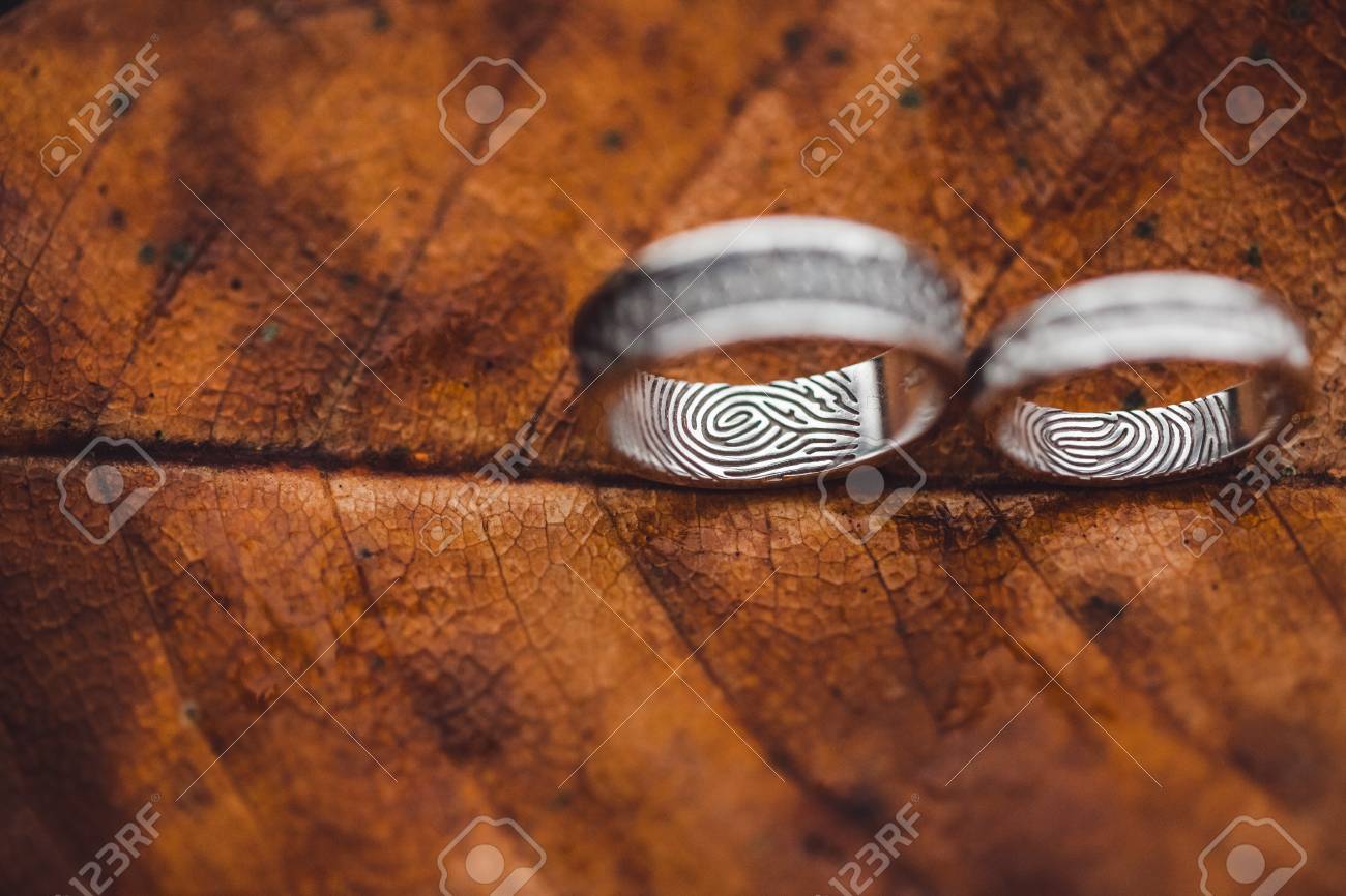 Wedding rings with fingerprints close-up on wet brown autumn leaf skeleton texture - 106840979 Wedding rings with fingerprints close-up on wet brown autumn leaf skeleton texture - 106840979