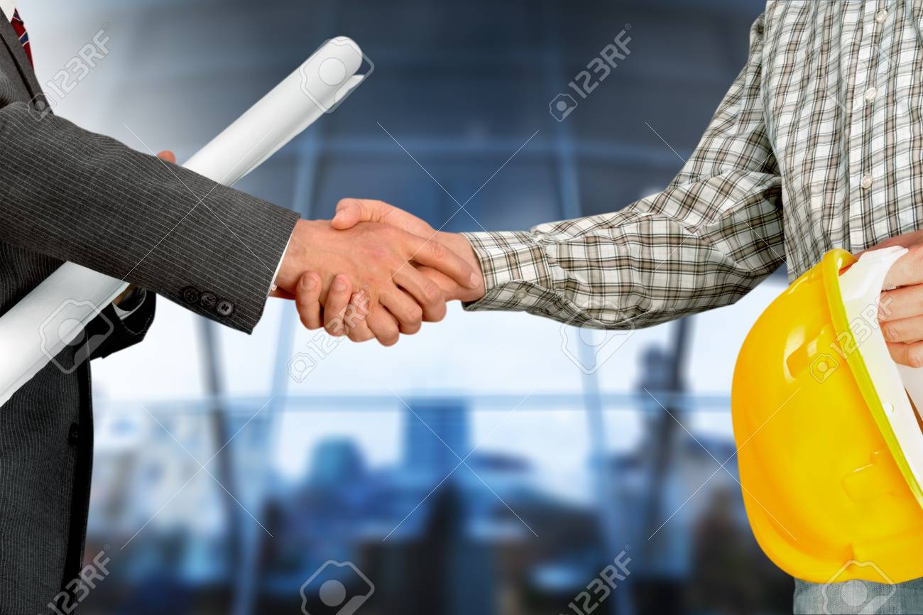 the office centre handsome construction workers in protective helmets and vests are shaking hands while working the office construction workers in protective helmets and vests the office centre handsome construction workers in protective helmets and vests are shaking hands while working the office construction workers in protective helmets and vests