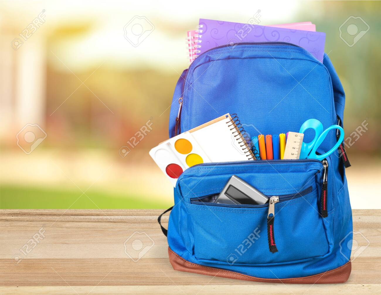 Colorful school supplies in backpack on wooden background - 125222423 Colorful school supplies in backpack on wooden background - 125222423