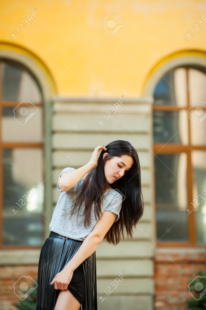 建物の近くでポーズかわいい若いモデル 灰色のシャツを着た甘い女性と黒い革のスカートが街を歩き回っている 現代自由ヒップスター人間の概念 の写真素材 画像素材 Image
