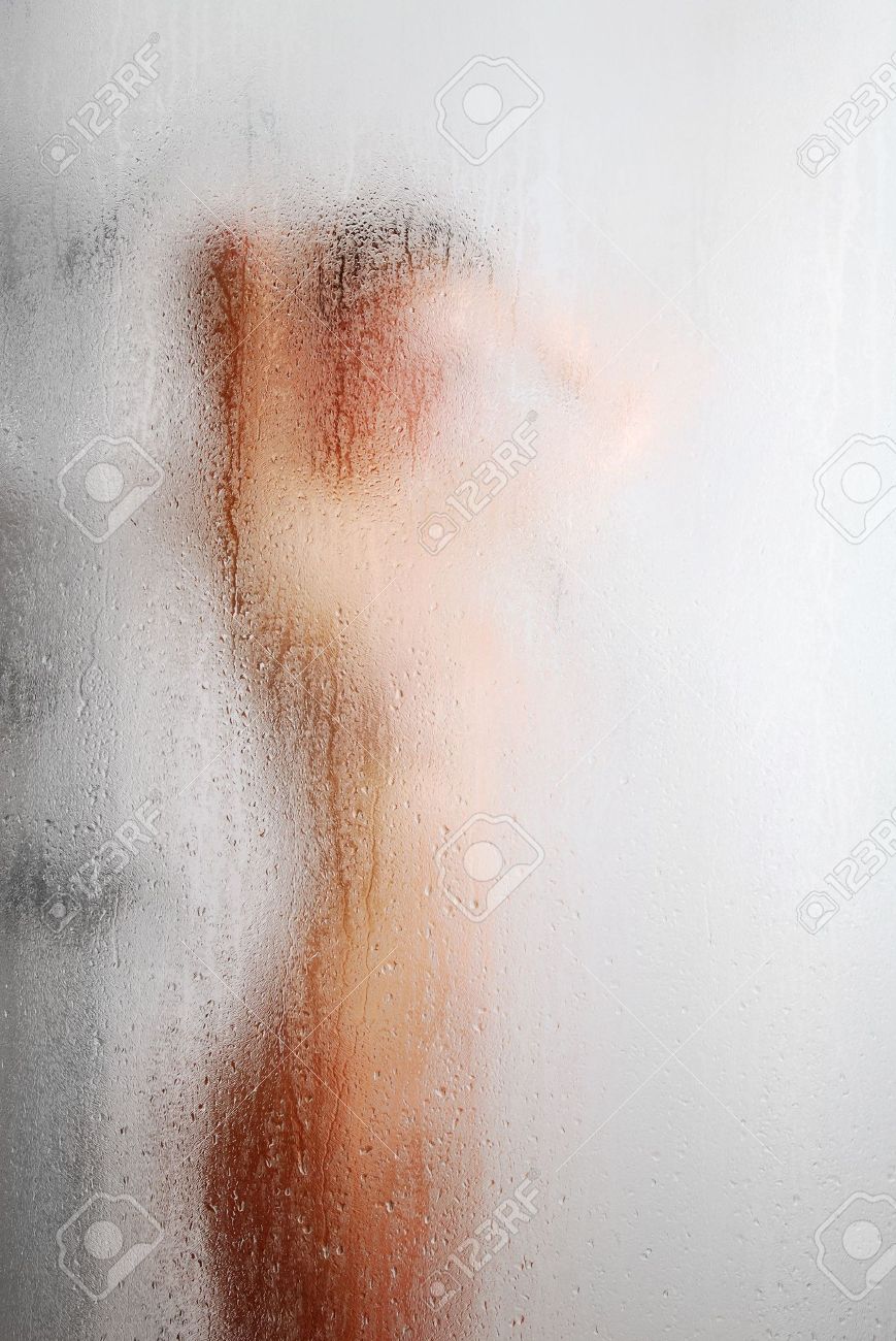 Chica Desnuda Tiene Una Ducha. Su Silueta Borrosa Es Casi Undistinguishable  A Través De La Superficie De Vidrio De Sudor Con Gotas De Agua Y Arroyos.  Enfoque Está En La Pared De
