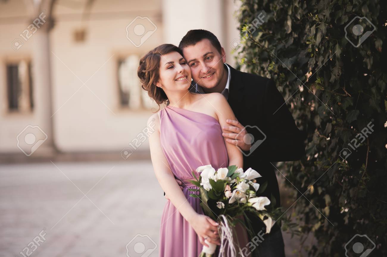 Happy wedding couple, groom, bride with pink dress hugging and..