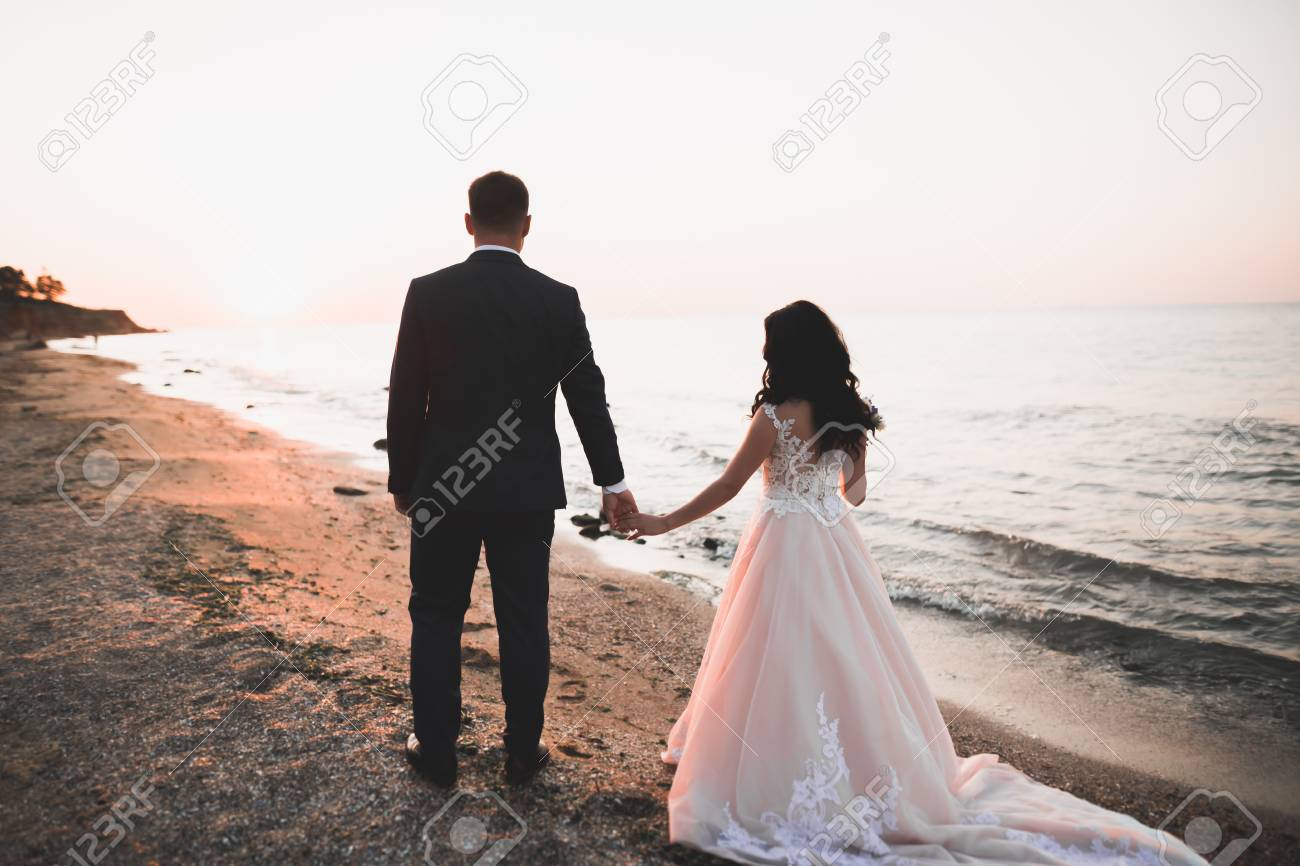 Happy and romantic scene of just married young wedding couple posing on beautiful beach. - 121556915 Happy and romantic scene of just married young wedding couple posing on beautiful beach. - 121556915