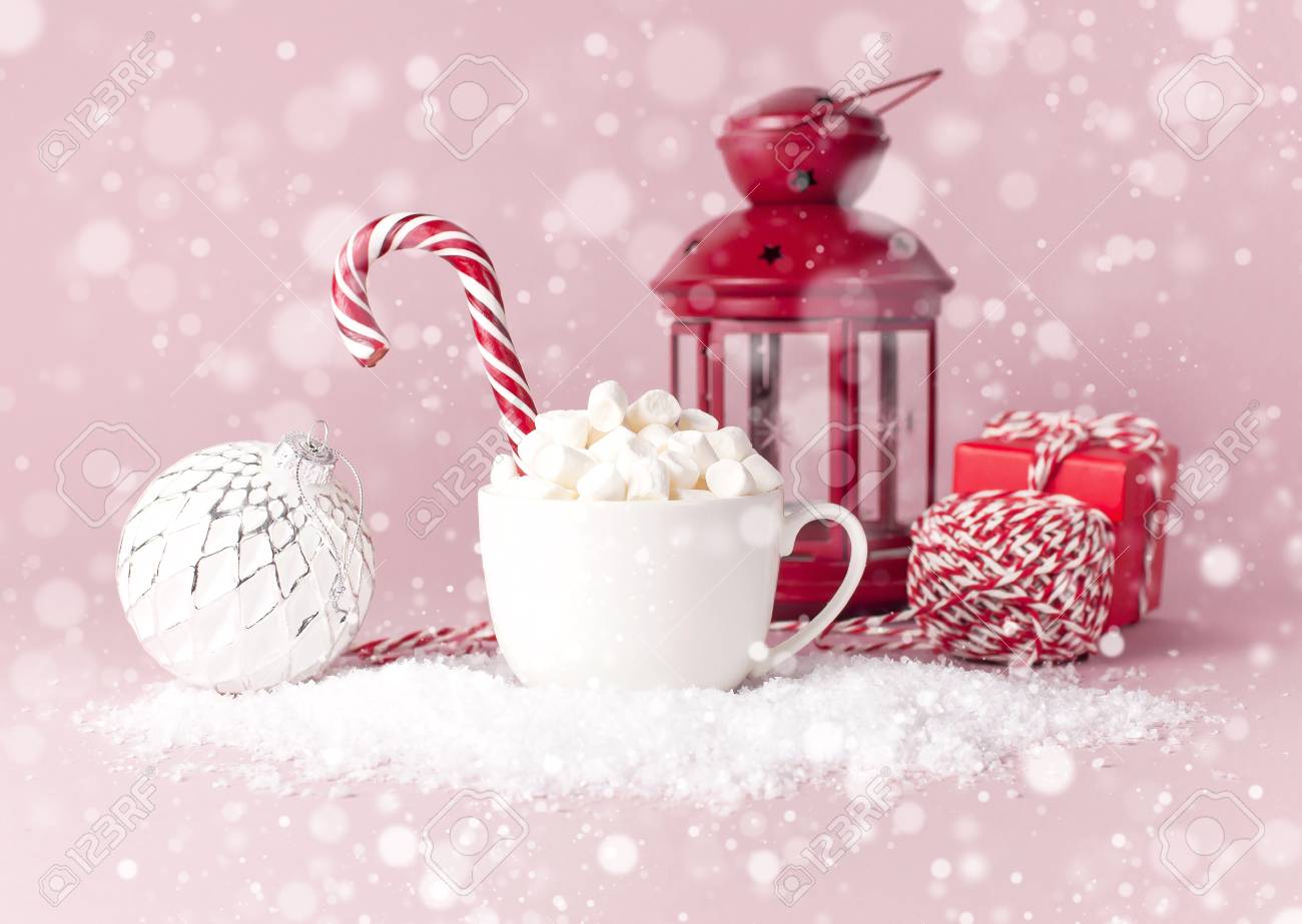 White mug with marshmallows Candy Cane gifts boxes Christmas New Year ball packaging lace flashlight in the snow on pink background Flat Lay. Winter traditional drink food Festive decor celebration - 112014396 White mug with marshmallows Candy Cane gifts boxes Christmas New Year ball packaging lace flashlight in the snow on pink background Flat Lay. Winter traditional drink food Festive decor celebration - 112014396
