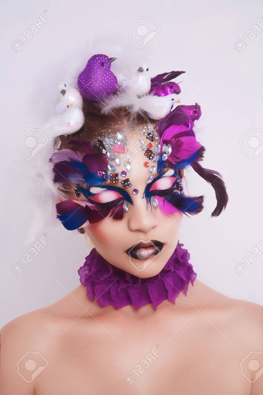 完璧な女性の顔のクローズ アップの肖像画 明るくする 紫色の唇 ピンク シャドウ 長いまつ毛 創造的な髪ドレス白紫鳥鳩メールの頭に座っています クレイジーなアート ファッションの新しいアイデア の写真素材 画像素材 Image