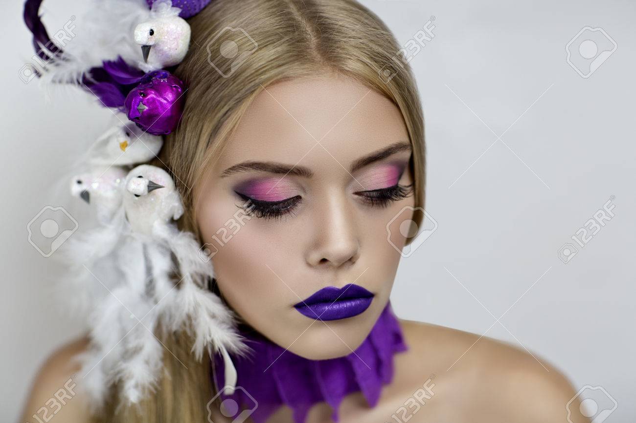 完璧な女性の顔のクローズ アップの肖像画 明るくする 紫色の唇 ピンク シャドウ 長いまつ毛 白紫鳥鳩メールの頭の上に座っていると金髪ストレートの髪 クレイジーなアート ファッションの新しいアイデア の写真素材 画像素材 Image