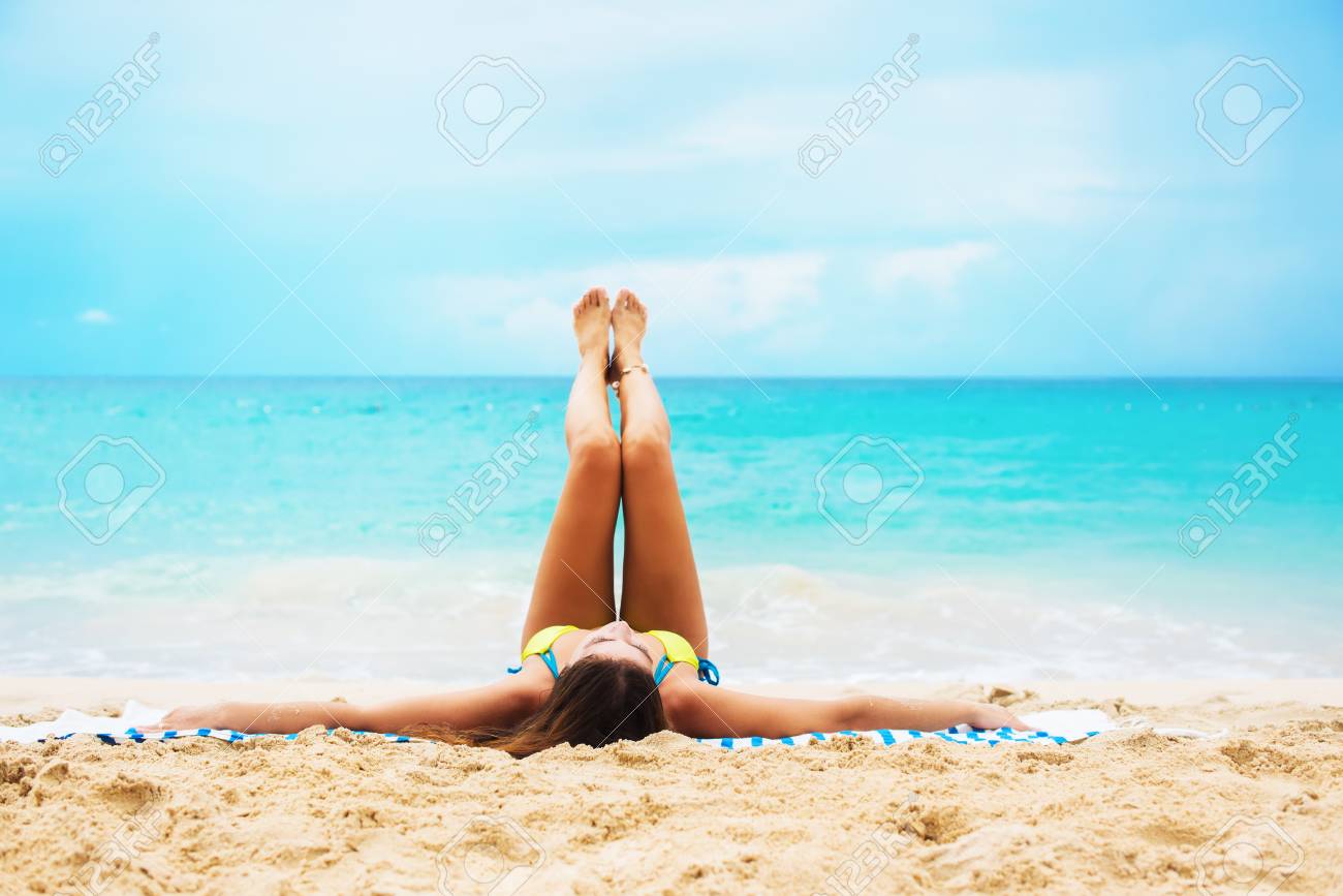 Young Suntan Woman Lying On Tropical Beach Stretching Up Slender Legs Before Blue Sea Background Summer Vacation Concept Stock Photo Picture And Royalty Free Image Image