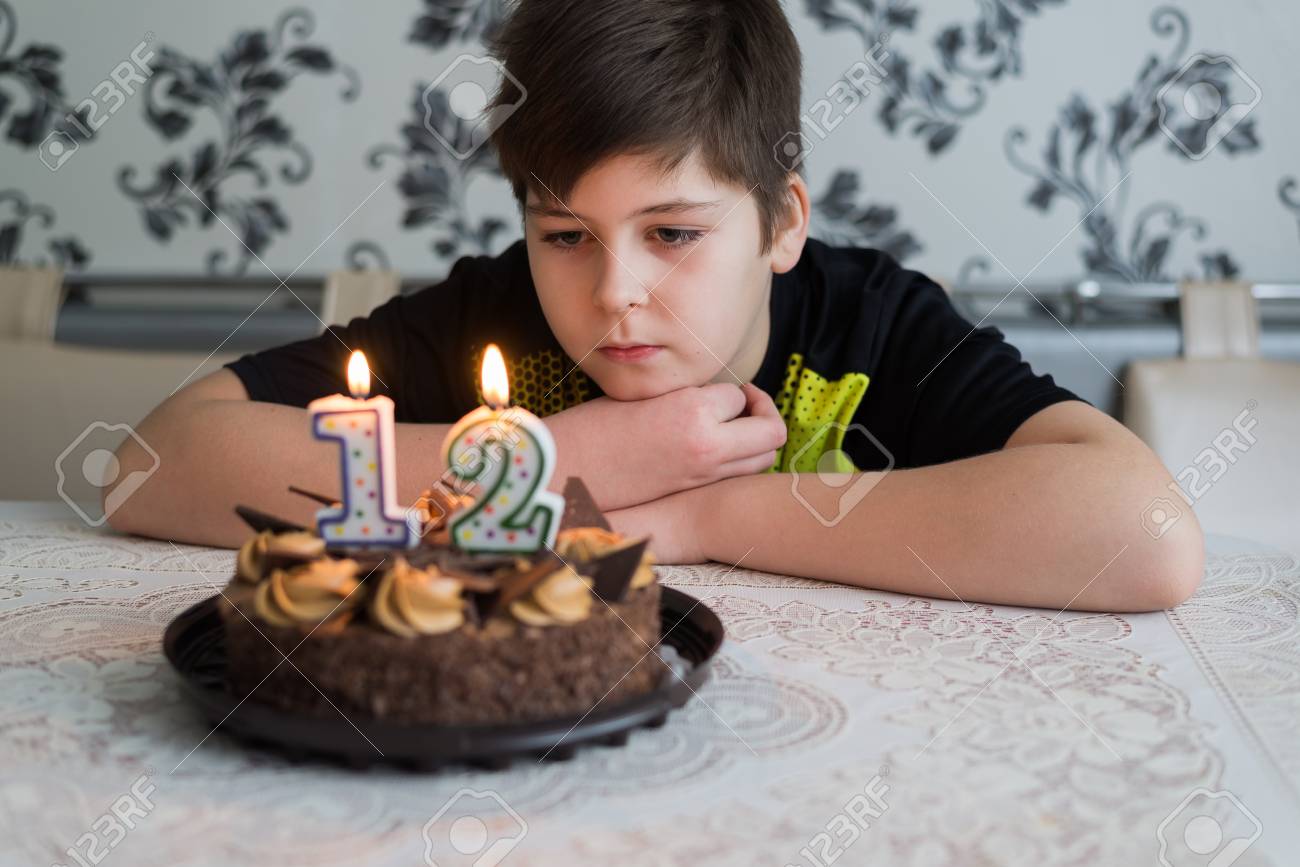 Garcon Adolescent Regarde Pensivement Un Gateau Avec Des Bougies Sur Le Douzieme Jour De Naissance Banque D Images Et Photos Libres De Droits Image