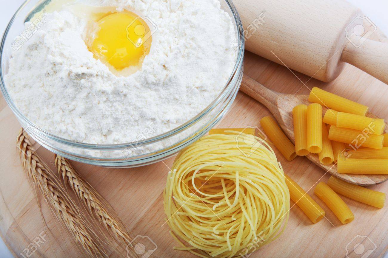 Bakery ingredient. Flour with raw eggs for making dough on the wooden board. - 18818439 Bakery ingredient. Flour with raw eggs for making dough on the wooden board. - 18818439