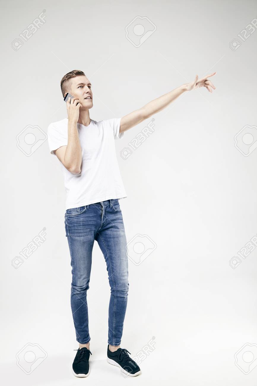 Stattlicher Kerl In Voller Lange Stehen Und Etwas Von Dem Ausgestreckten Arm Zeigt Mit Handy Isoliert Auf Weissem Hintergrund Tragen Jeans Und T Shirt Lizenzfreie Fotos Bilder Und Stock Fotografie Image 71890814