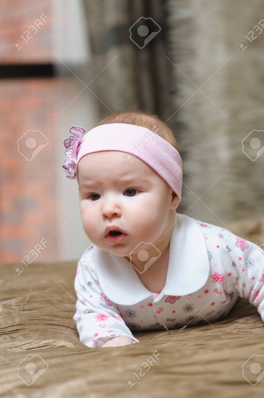 Baby Girl Lying On Belly On Bed In Bedroom With Golden Linens Charming 5 Month Old Girl Smiling And Grimacing Home Interior In Background Stock Photo Picture And Royalty Free Image Image