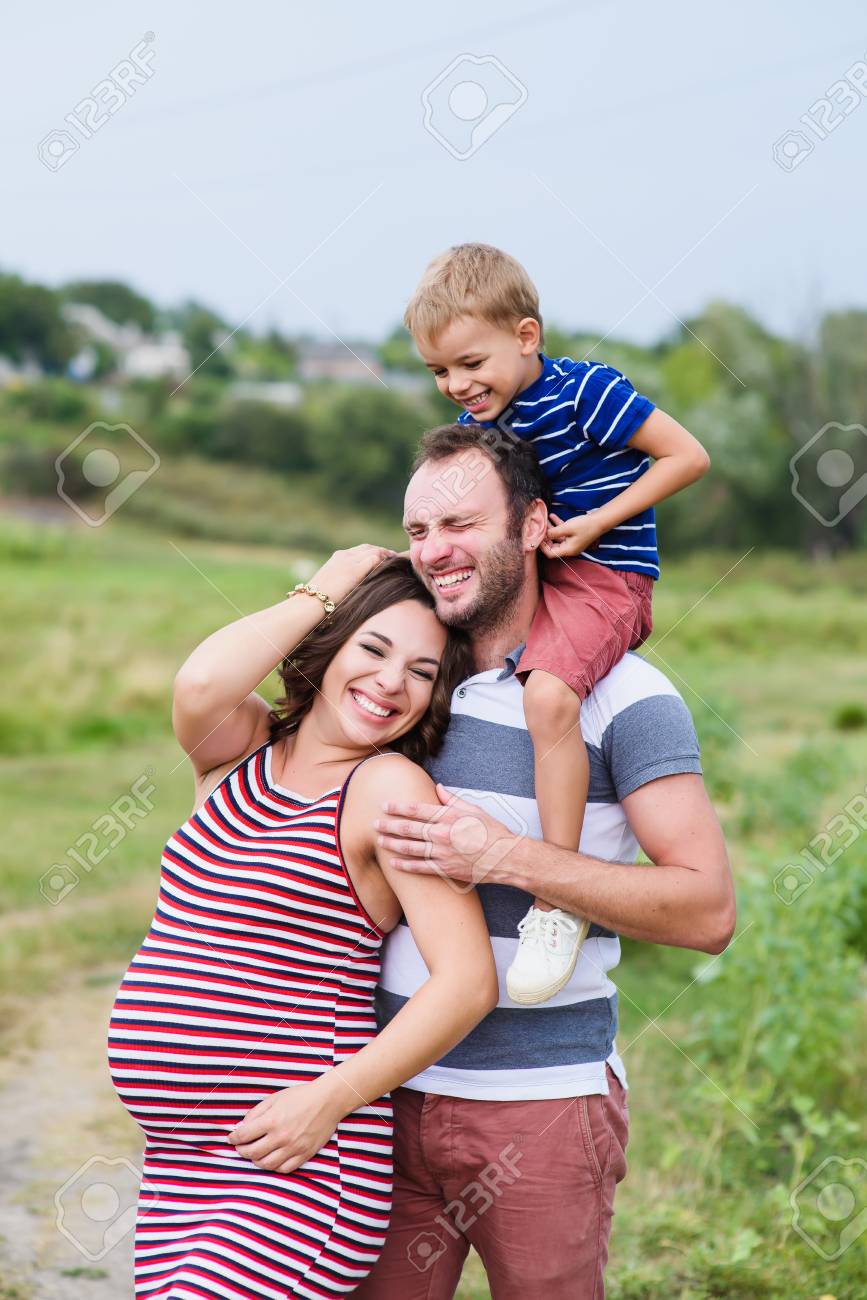 Familia Embarazada De Tres En Espera De Bebe Padre Madre E Hijo Jugando Juntos En El Dia Fuera Gente Feliz Abrazando Sonriente Bebe Riendo Sentado Sobre Los Hombros De Papa Fotos Retratos