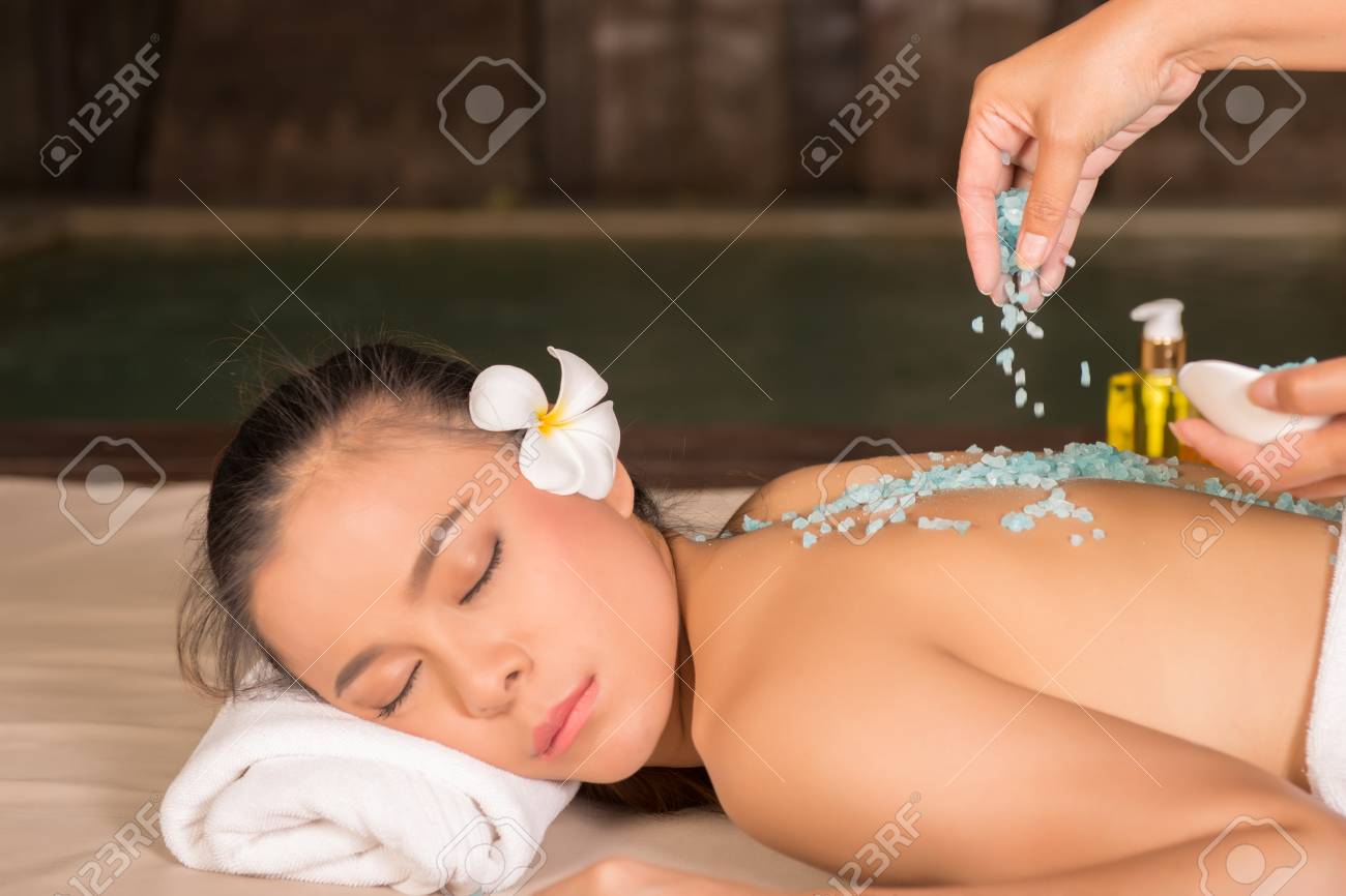 spa therapist applying scrub salt on young woman back at spa stock spa therapist