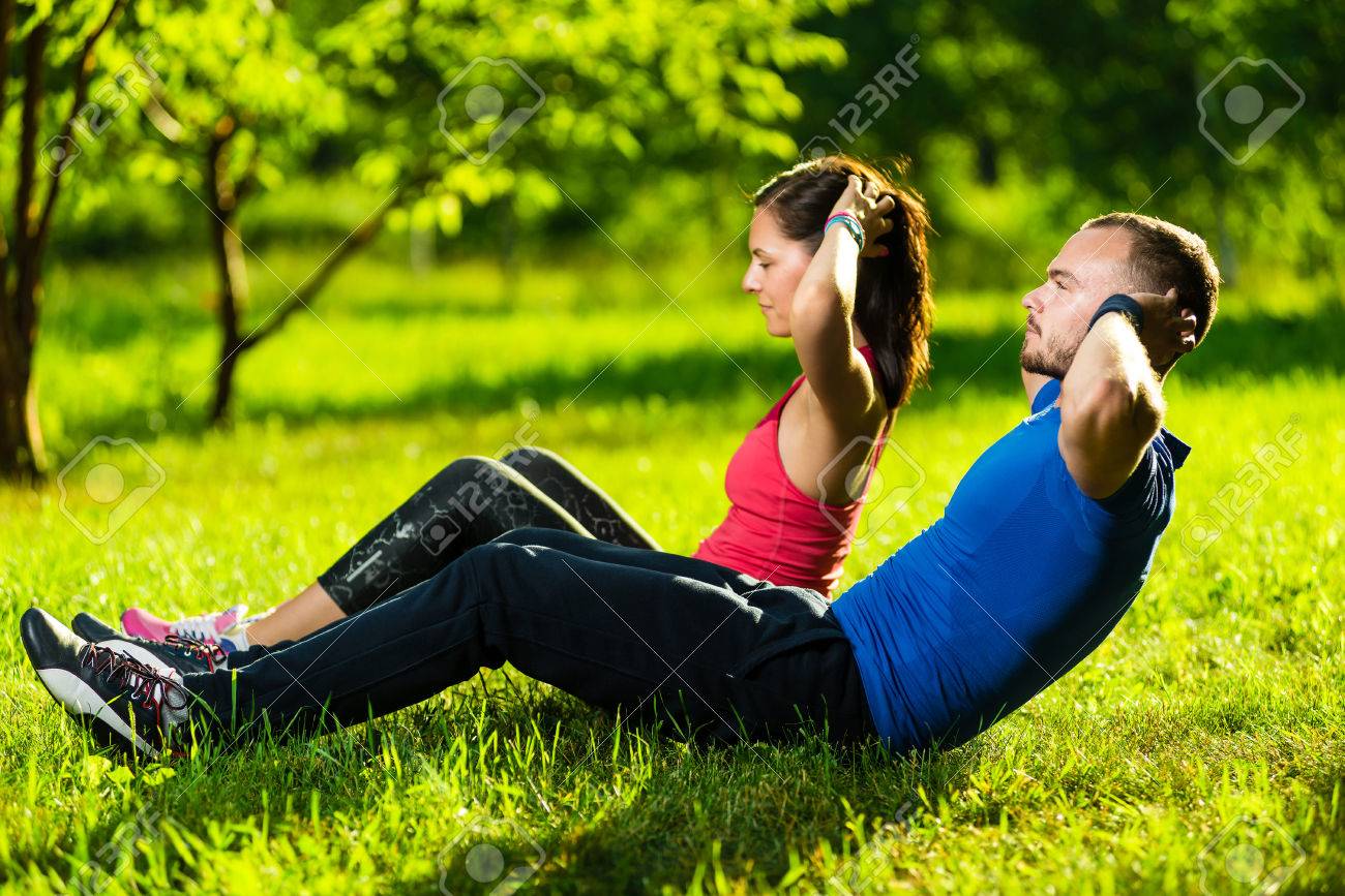 Man and woman exercising at the city park. Beautiful young multiracial couple. Sit ups fitness couple exercising outside in grass. Fit happy people working out outdoor. - 39993245 Man and woman exercising at the city park. Beautiful young multiracial couple. Sit ups fitness couple exercising outside in grass. Fit happy people working out outdoor. - 39993245