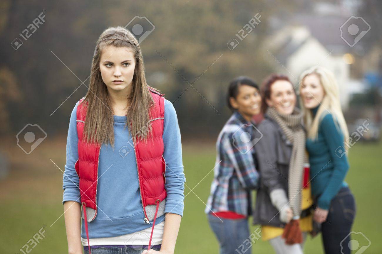 Upset Teenage Girl With Friends Gossiping In Background - 7178072 Upset Teenage Girl With Friends Gossiping In Background - 7178072