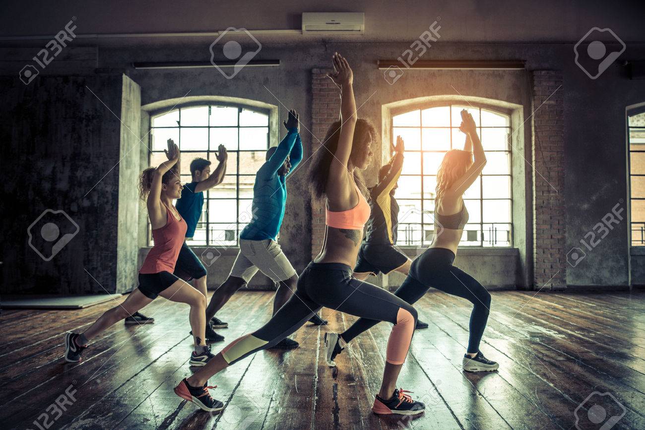 Group of sportive people in a gym training - Multiracial group of athletes stretching before starting a workout session - 57814540 Group of sportive people in a gym training - Multiracial group of athletes stretching before starting a workout session - 57814540