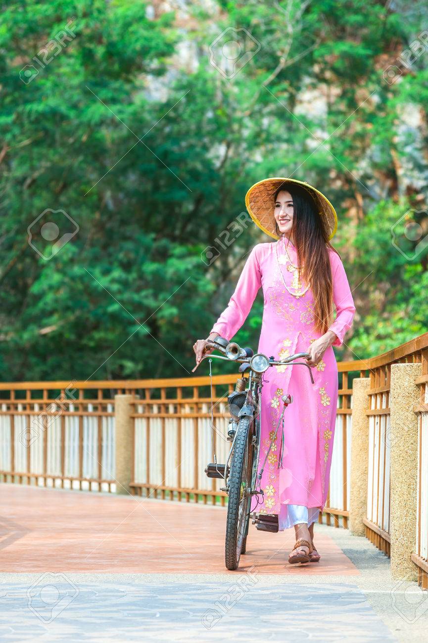 ベトナムの少女の伝統的な衣装 アオザイの肖像画はベトナムで女性のための有名な伝統的な衣装 ビンテージ自転車とベトナムの民族衣装を身に着けている美しい若いアジア女性 の写真素材 画像素材 Image