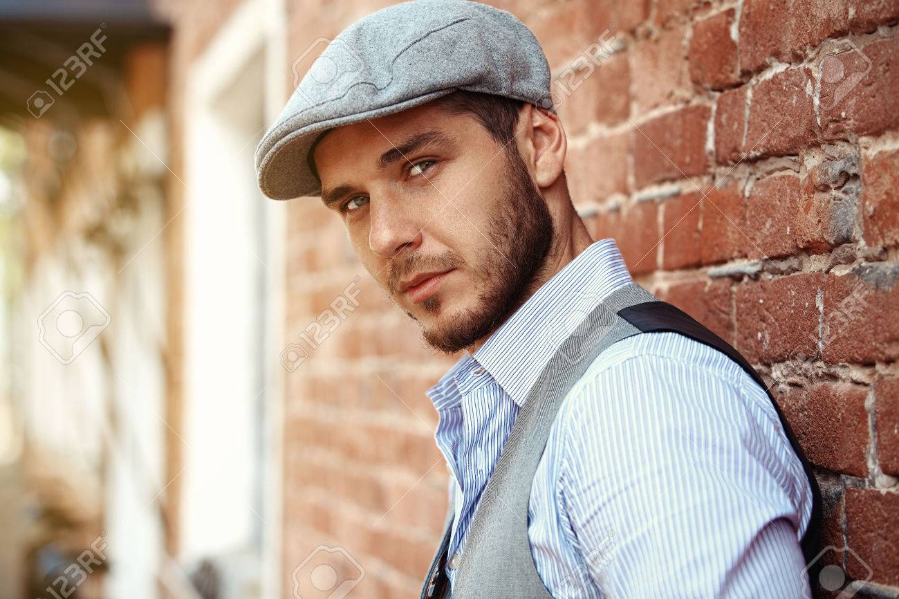 casual young man stands with his back against a brick wall - 50162766 casual young man stands with his back against a brick wall - 50162766