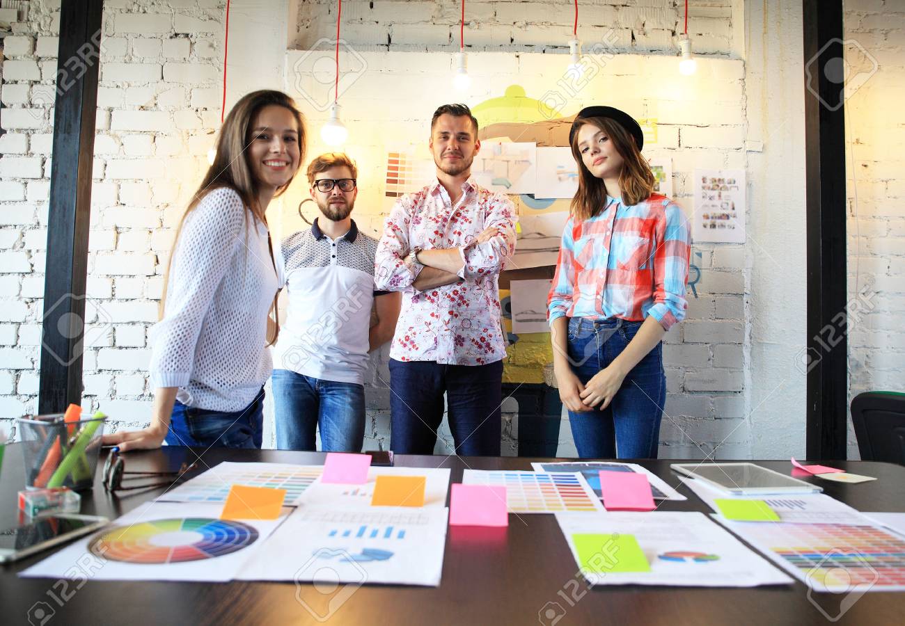 Portrait of happy young people in a meeting looking at camera and smiling. Young designers working together on a creative project - 73276559 Portrait of happy young people in a meeting looking at camera and smiling. Young designers working together on a creative project - 73276559