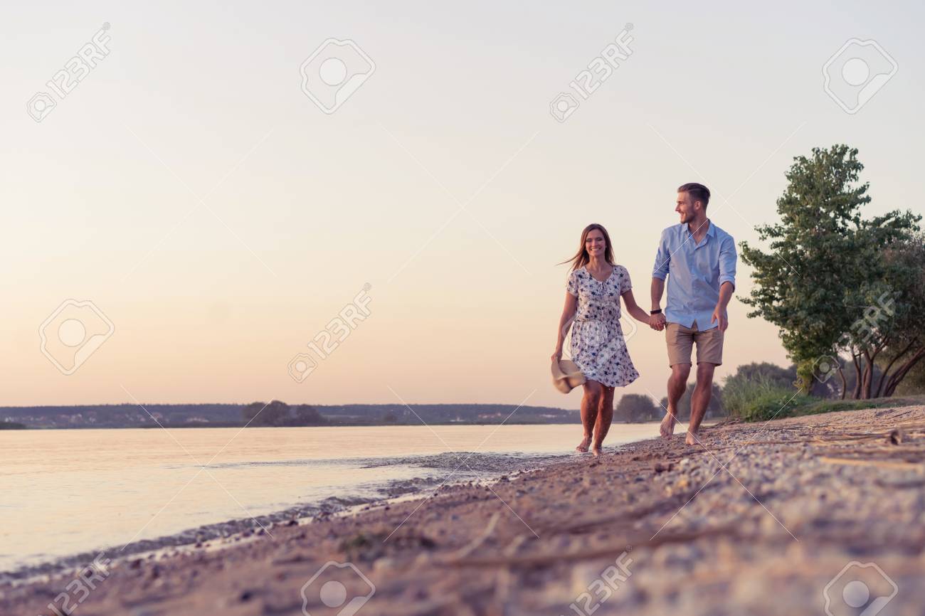 couple walking on the beach at sunset ロイヤリティーフリーフォト