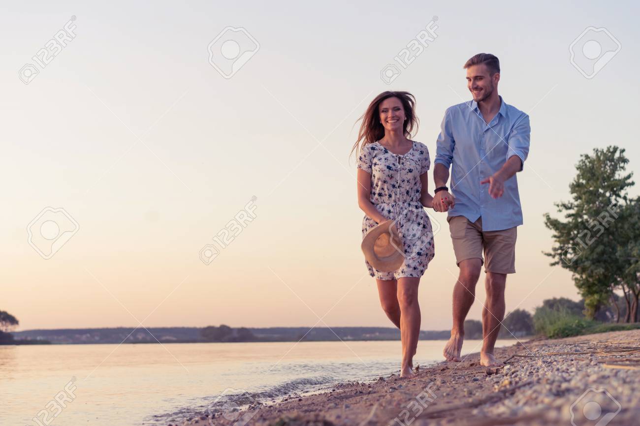 couple walking on the beach at sunset ロイヤリティーフリーフォト