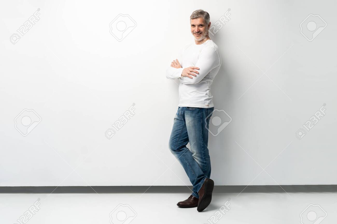 Full body portrait of relaxed mature man standing with arms crossed over white background. - 123587276 Full body portrait of relaxed mature man standing with arms crossed over white background. - 123587276