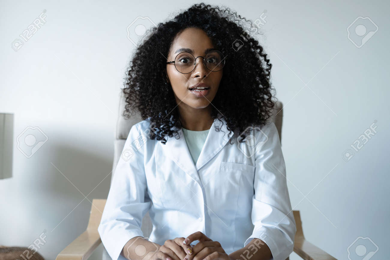Mixed race woman doctor talking online with patient, making video call, looking at camera - 170765782 Mixed race woman doctor talking online with patient, making video call, looking at camera - 170765782