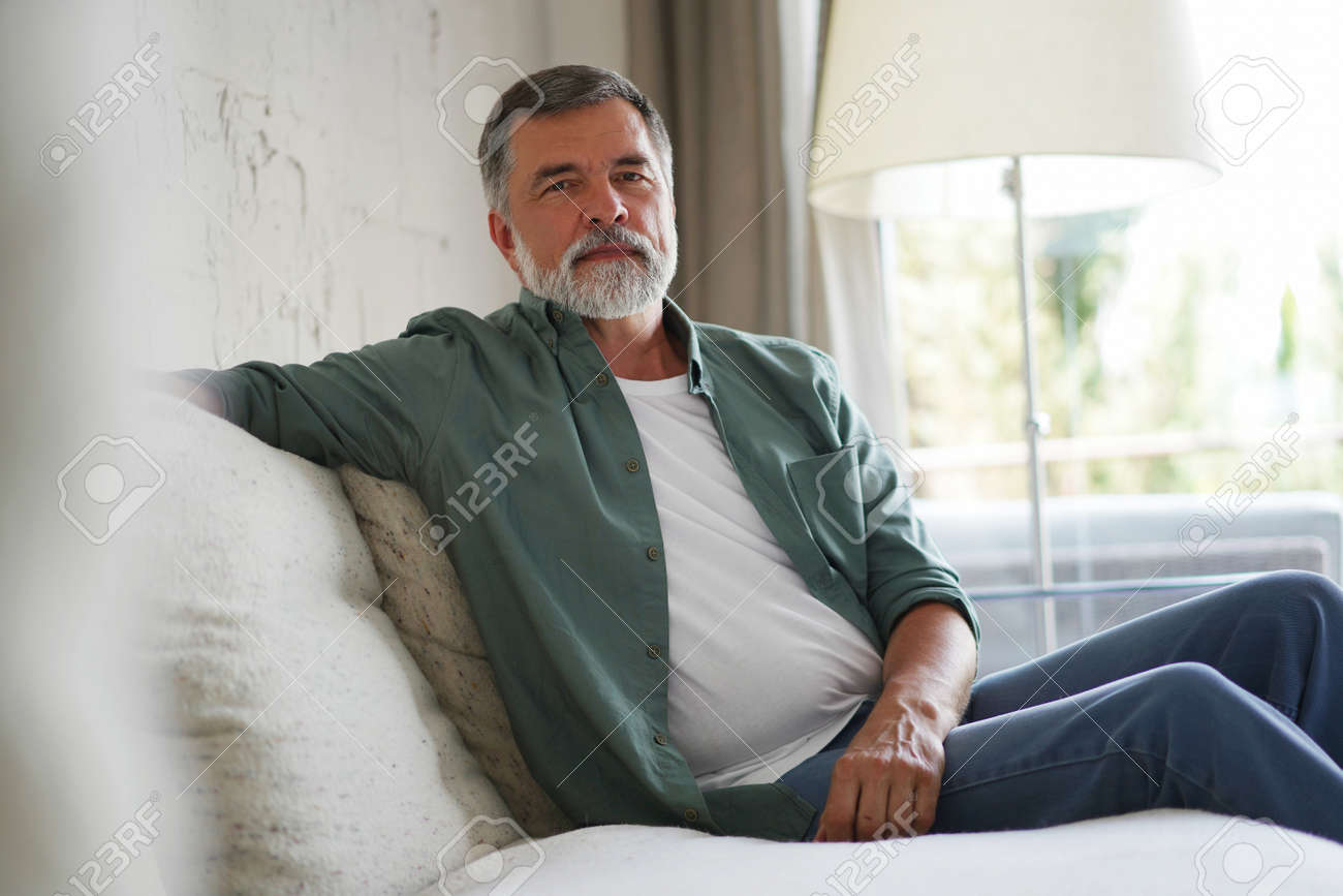Portrait of attractive senior man sitting in sofa at home. - 171566677 Portrait of attractive senior man sitting in sofa at home. - 171566677