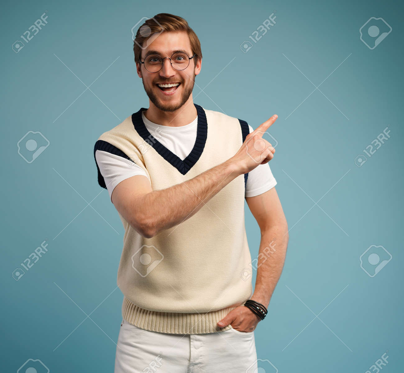 Portrait of a happy young man in casual pointing fingers away at copy space isolated over blue background. - 171574360 Portrait of a happy young man in casual pointing fingers away at copy space isolated over blue background. - 171574360