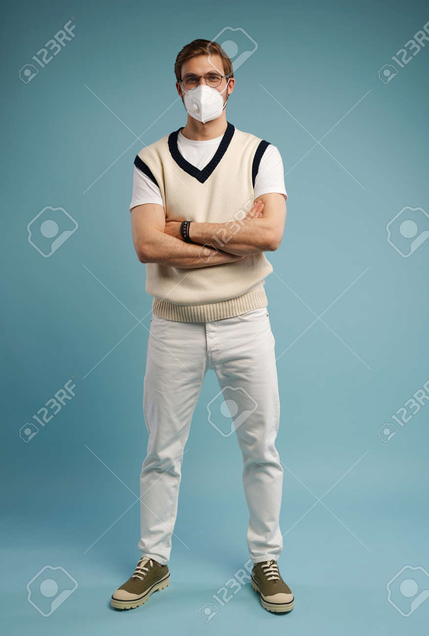 Portrait of handsome young man with surgical medical mask in casual style shirt standing, looking at camera with smile - 171597158 Portrait of handsome young man with surgical medical mask in casual style shirt standing, looking at camera with smile - 171597158
