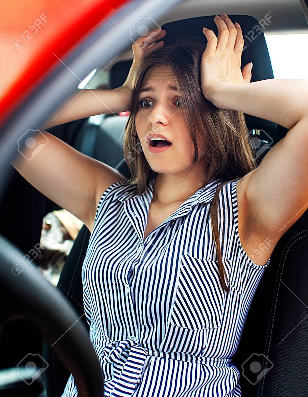 Young woman touching her head by hands while she sitting in a car. - 148148065 Young woman touching her head by hands while she sitting in a car. - 148148065