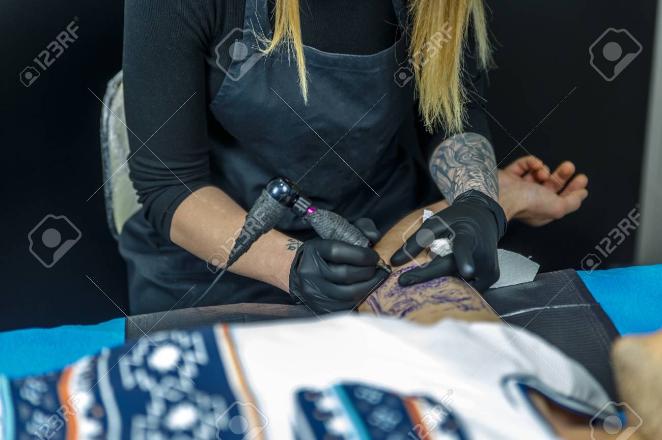 刺青アーティストの女の子を慎重にタトゥー マシン 入れ墨のアウトラインを描画します の写真素材 画像素材 Image