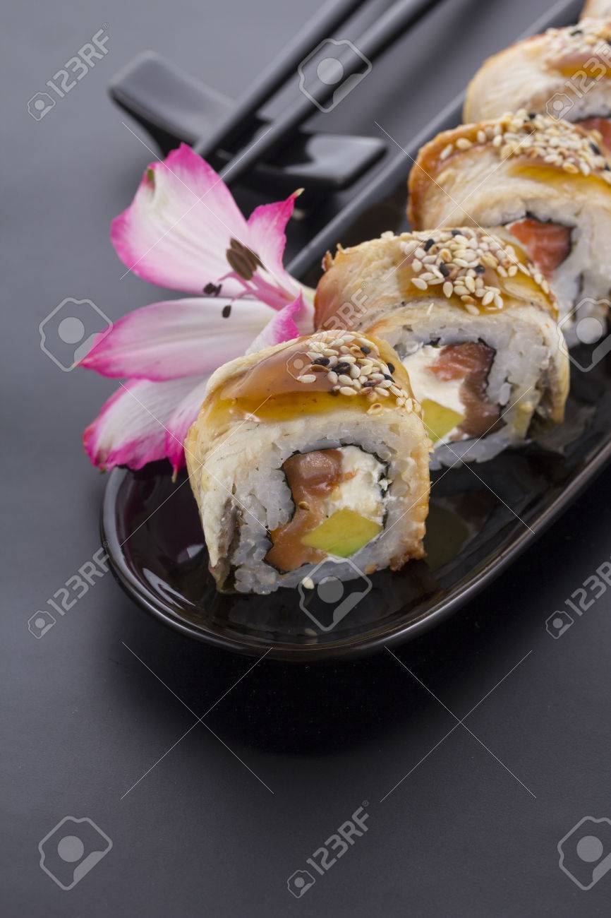 Eel Sushi Roll On A Black Plate With Flower Decoration Stock Photo Eel Sushi Roll On A Black Plate With Flower Decoration Stock Photo 53780536