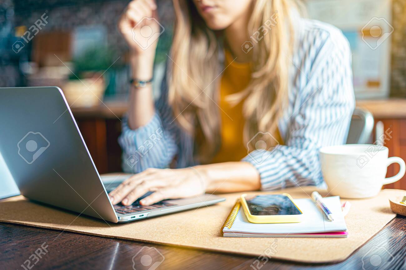 Home office woman and distance learning online education. Cropped beautiful lady girl working at notebook at kitchen and drinking coffee at home. Using computer and online shops. - 148673648 Home office woman and distance learning online education. Cropped beautiful lady girl working at notebook at kitchen and drinking coffee at home. Using computer and online shops. - 148673648