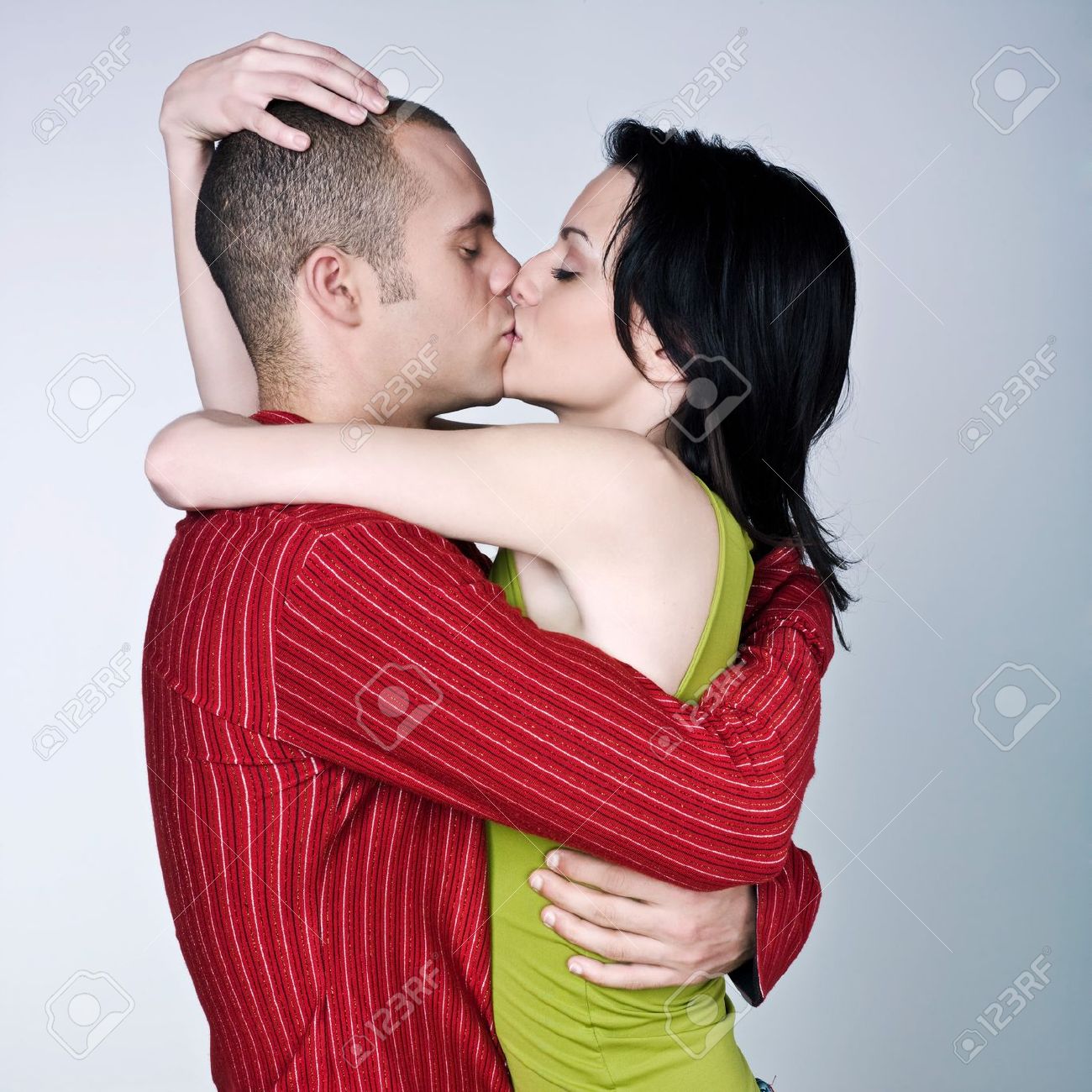 1 つの若いカップルがスタジオにキスしてハグ分離灰色の背景 の写真素材 画像素材 Image