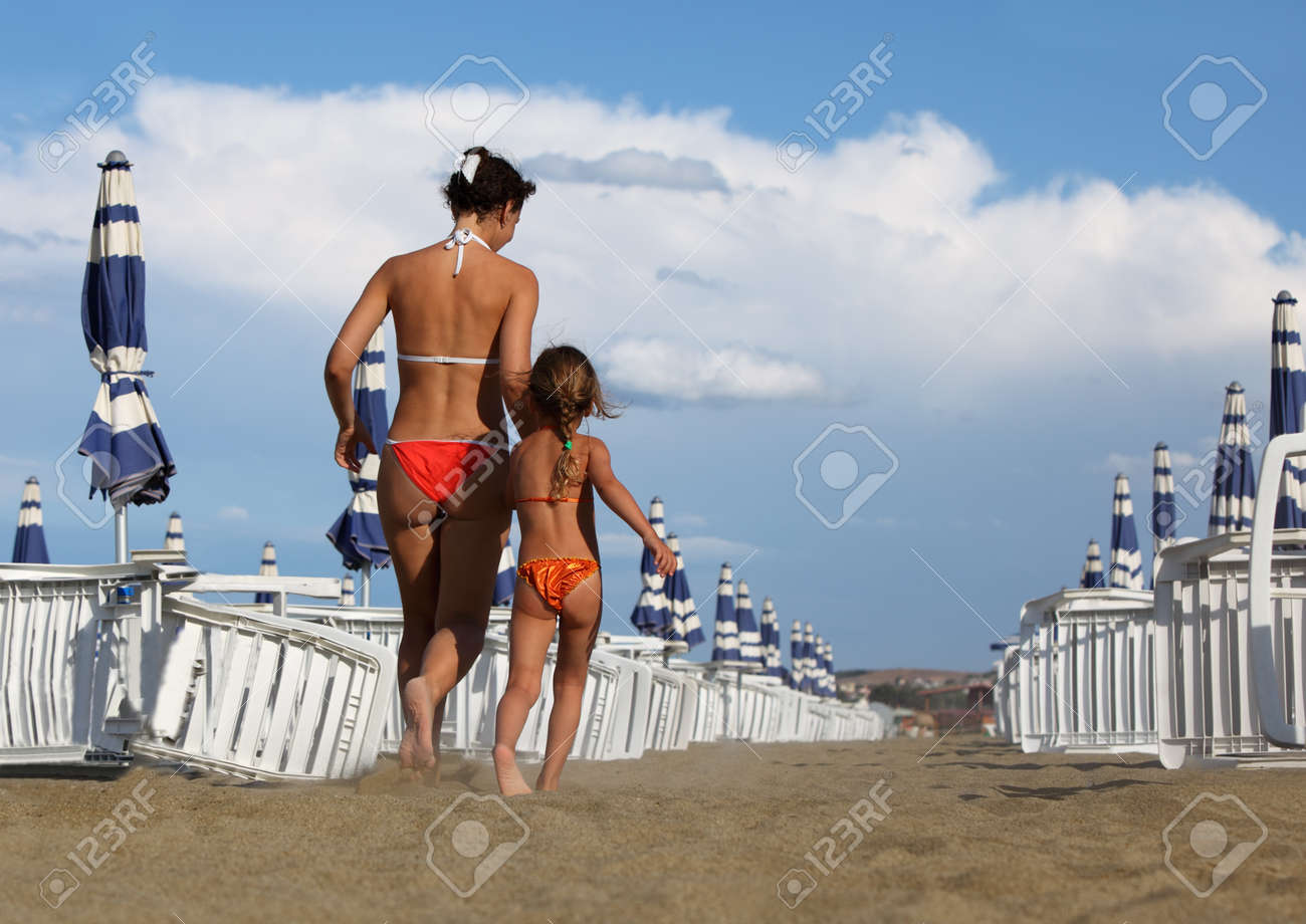 娘　水着 若い母親と娘水着ビーチに行きます。母娘の手、白いラウンジャーと青いパラソルの行を保持します。の写真素材・画像素材 Image 17635613