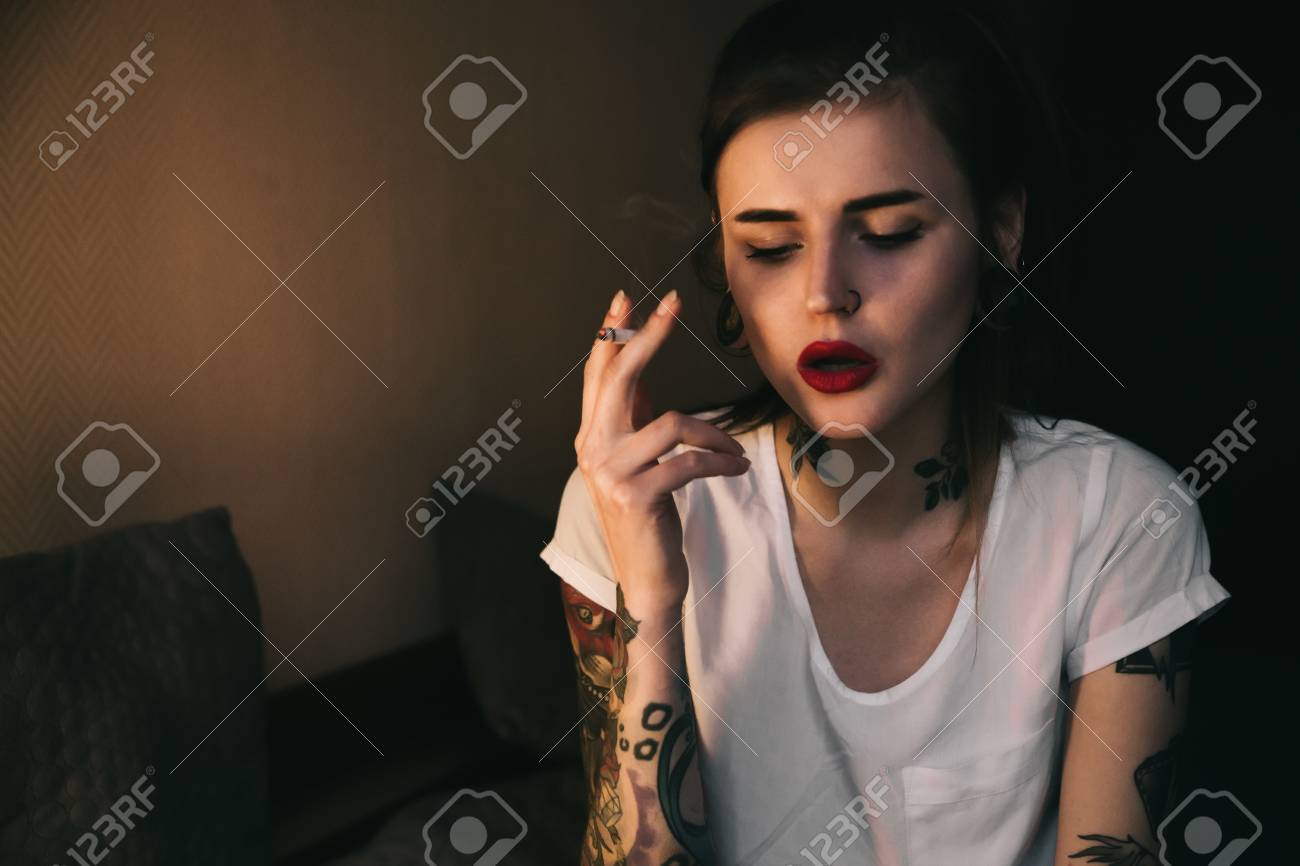 Junge Tatowierte Frau Raucht Im Zimmer Mit Warmem Weichem Haar Das Rotes Lippenstift Und Weisses T Shirt Tragt Lizenzfreie Fotos Bilder Und Stock Fotografie Image 84651180
